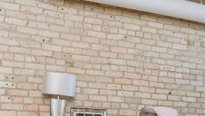 En mysig arbetsplats med en tegelvägg, ett skrivbord, en stol, en lampa och en radio.