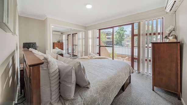 A bedroom with a large bed, a wooden desk, a dresser, and a sliding glass door leading to a balcony. - Brilliant Apartment on Brisbane - Walk Everywhere! (Dubbo)