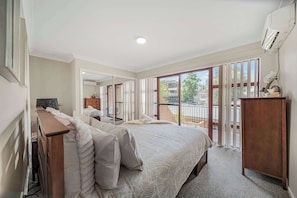 A bedroom with a large bed, a wooden desk, a dresser, and a sliding glass door leading to a balcony. - Brilliant Apartment on Brisbane - Walk Everywhere! (Dubbo)