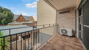 A balcony with a brick wall, a fan, and a view of neighboring buildings. - Brilliant Apartment on Brisbane - Walk Everywhere! (Dubbo)