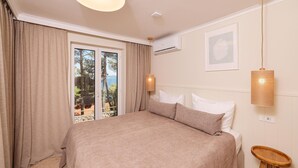 A bedroom with a large bed, a view of the sea through the window, and a ceiling fan. - Cozy apartment in Kukljica with WiFi (Kukljica)