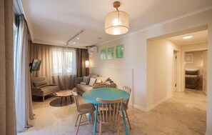 A modern living room with a sofa, a round table, and a dining area with chairs.