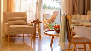 A living room with a sofa, a chair, a small table with a bowl of fruit, and a view through a glass door. - Lovely apartment in Kukljica with house sea view (Kukljica)