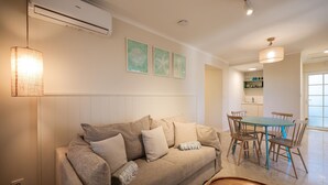 A living room with a beige sofa, a dining table with chairs, and a kitchen area in the background. - Lovely apartment in Kukljica with house sea view (Kukljica)