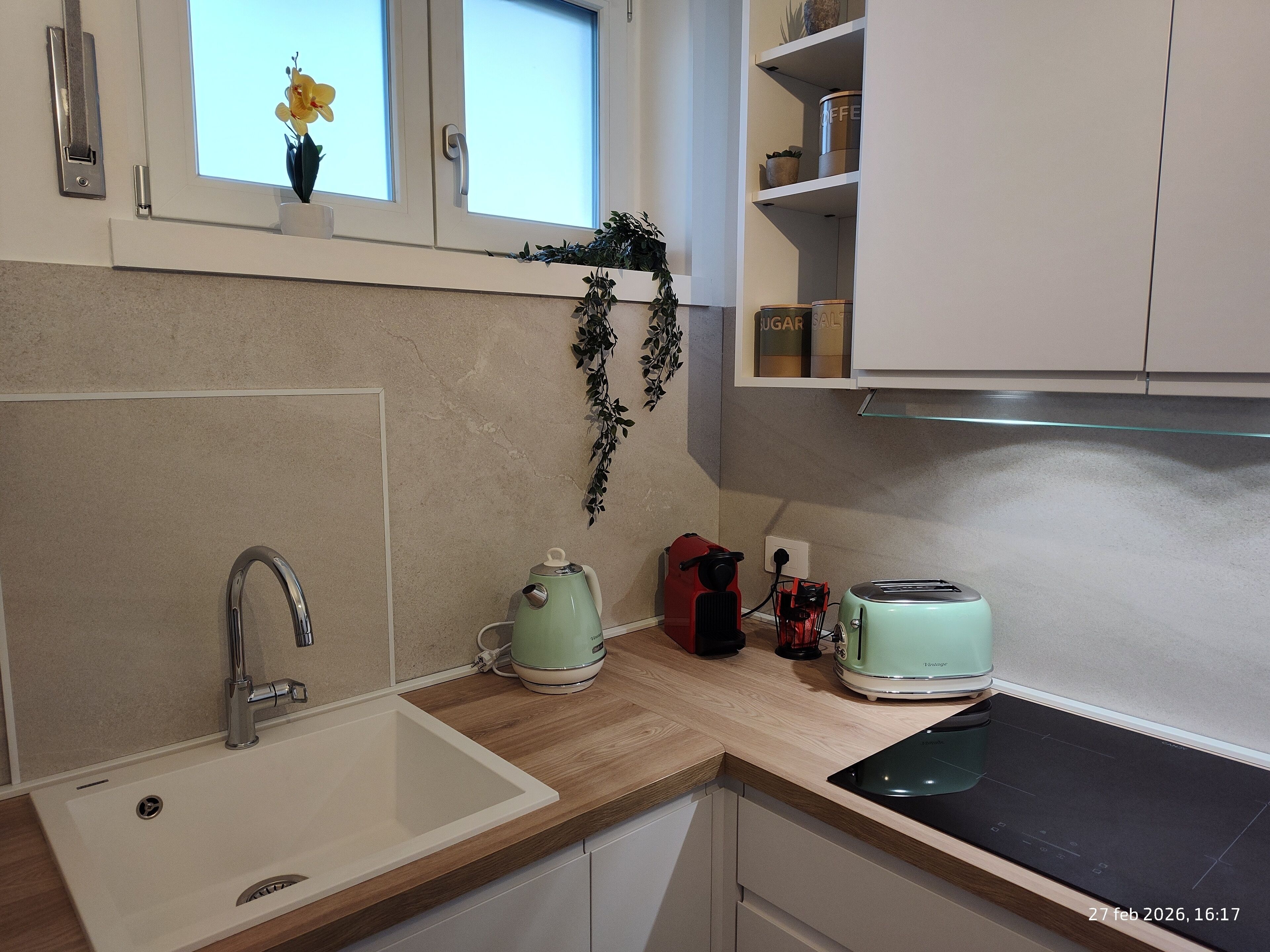 A kitchen with a sink, a toaster, a kettle, and a stove.