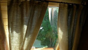 A room with a skylight, wooden walls, and curtains tied at the top. - Gîte de Brion en Cézallier (COMPAINS)