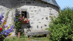 A rustic stone building with a sloped roof, a small window, and a bench in front. - Gîte de Brion en Cézallier (COMPAINS)