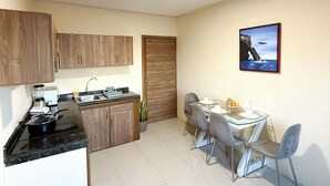 Cocina compacta con comedor, que presenta una encimera de granito, armarios de madera, una planta en maceta y una mesa para dos.