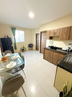 A modern kitchen with wooden cabinets, a dining table set for four, and a small dining area with chairs. - The Perfect Apartment in the Galapagos: Comfort, Elegance, and a Prime Location (Santa Cruz)