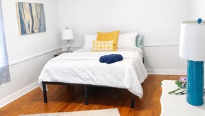 Un dormitorio con cama, mesita de noche, lámpara y alfombra.