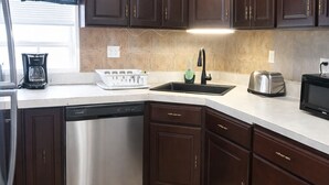 Una cocina moderna con armarios de madera oscura, electrodomésticos de acero inoxidable y suelo de madera.
