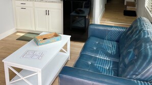 A compact living space with a kitchenette, a blue sofa, and a small table.