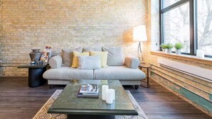 Ein Wohnzimmer mit Backsteinwand, einer Couch, einem Couchtisch und einer Lampe.