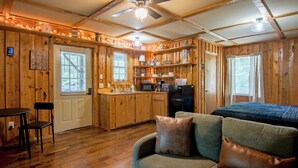 A cabin interior with a kitchen, dining area, and a sofa. - Cozy, Modern Black Cabin Retreat - Mins. to Cloudland Canyon & Lookout Mountain (Rising Fawn)