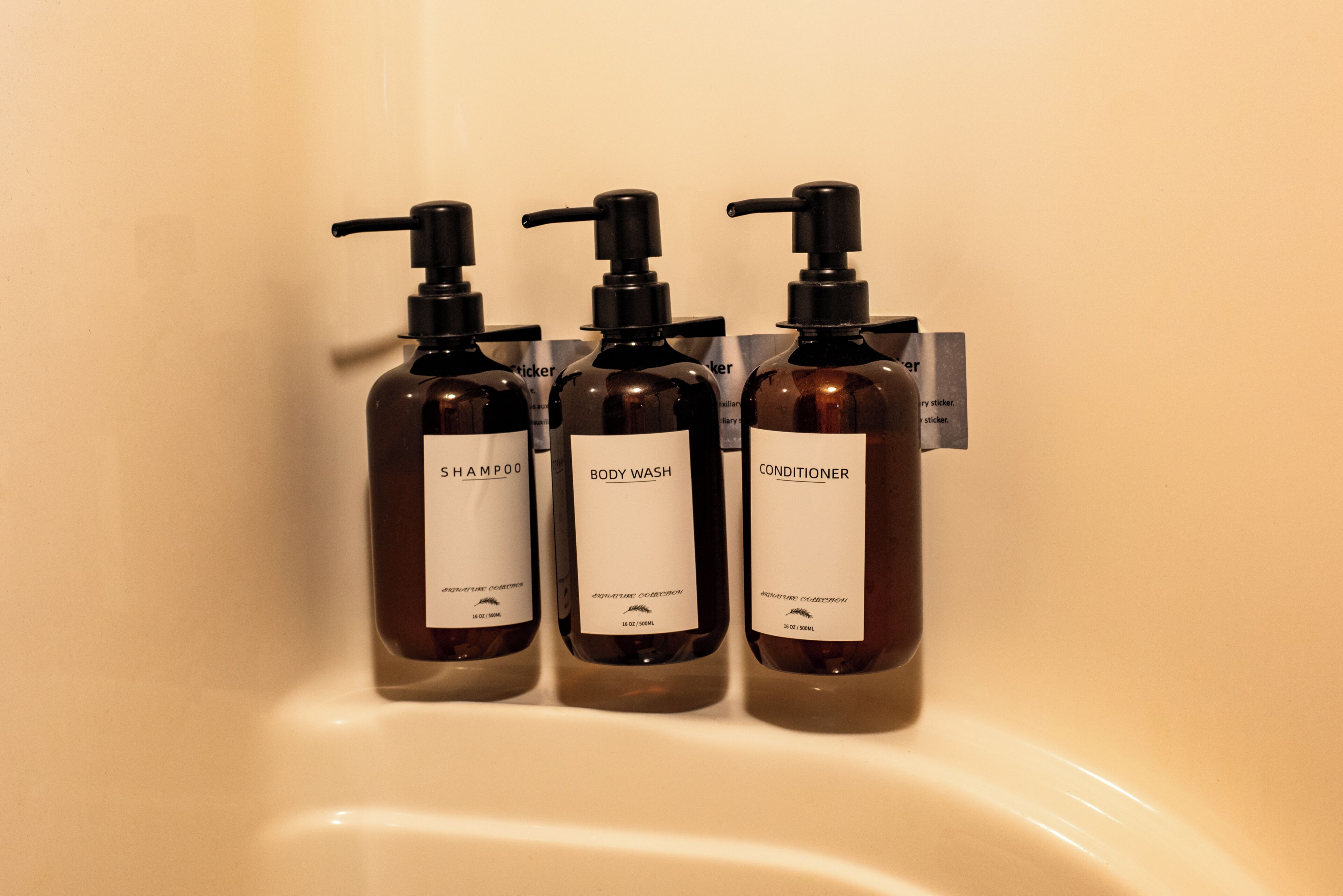 Drei Flaschen Shampoo, Duschgel und Spülung in einem Badezimmerwaschbecken.