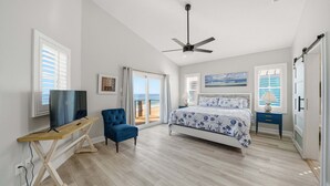 Une chambre à coucher avec un lit, une télévision, une chaise et un ventilateur de plafond.