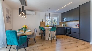 Een moderne keuken met een centraal eiland, een bar met barkrukken en een eethoek met een tafel gedekt voor vier personen.