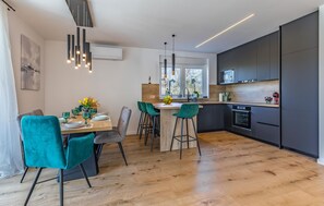 A modern kitchen with a central island, bar stools, and a dining area with a table set for four. - Gorgeous home in Nedescina with WiFi (Nedescina)