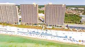 A beachfront hotel with multiple high-rise buildings, a sandy beach with numerous umbrellas, and a clear view of the ocean. - Book Now! New Listing! Beachfront 2 bedroom at Splash Resort! (Panama City Beach)