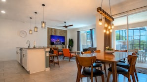 A modern kitchen with a dining area, large windows, and a ceiling fan. - Spacious 4BR Townhome w/ Private Pool • Storey Lake Resort • Near Disney (Kissimmee)