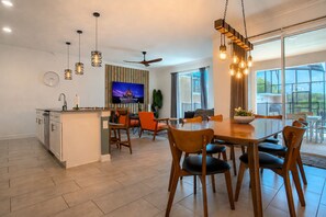 A modern kitchen with a dining area, large windows, and a ceiling fan. - Spacious 4BR Townhome w/ Private Pool • Storey Lake Resort • Near Disney (Kissimmee)