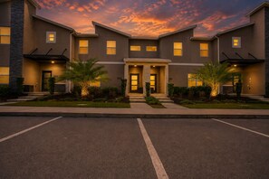 A modern multi-story building with a symmetrical facade, large windows, and a well-lit entrance. - Spacious 4BR Townhome w/ Private Pool • Storey Lake Resort • Near Disney (Kissimmee)