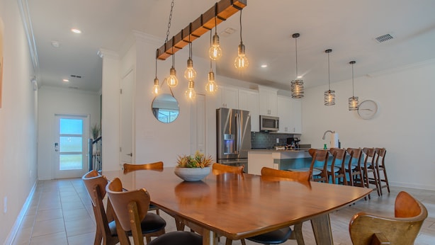 A modern kitchen with a central island, stainless steel appliances, and hanging light fixtures. - Spacious 4BR Townhome w/ Private Pool • Storey Lake Resort • Near Disney (Kissimmee)