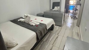 A hotel room with a bed, a dresser, a mirror, and a view of a pool. - Studio Au Centre-ville à 2 Minutes de la Plage 105 (Sosúa)
