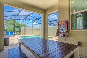 Ein überdachter Außenbereich mit Pool, Liegestühlen und einem Tisch.