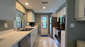 A compact kitchen with white cabinets, a stainless steel sink, and a built-in oven. - Sunny Siesta Key Retreat w/ Private Heated Pool | 2BR | Dog-Friendly (Siesta Key)