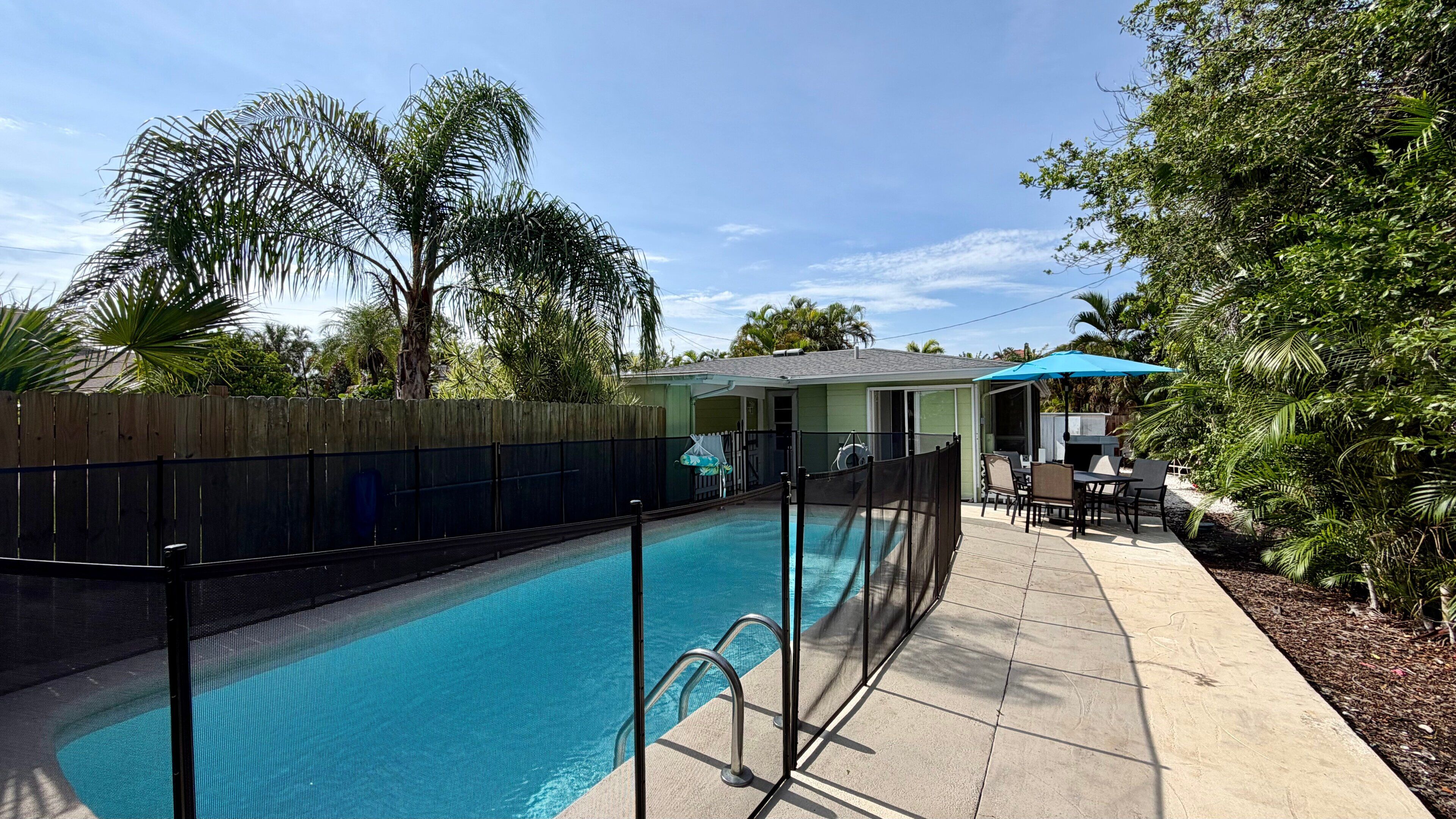 Ein Garten mit Swimmingpool, einem umzäunten Patio und einer überdachten Sitzgruppe.