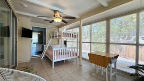 A room with bunk beds, a ceiling fan, a TV, and large windows. - Sunny Siesta Key Retreat w/ Private Heated Pool | 2BR | Dog-Friendly (Siesta Key)