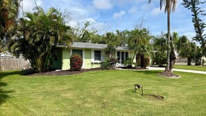 Una propiedad residencial con una casa verde, césped y varios árboles.