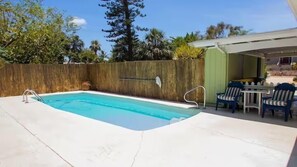 A rectangular swimming pool with a wooden fence and a patio area with chairs and a table. - Sunny Siesta Key Retreat w/ Private Heated Pool | 2BR | Dog-Friendly (Siesta Key)