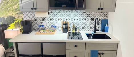 A compact kitchen with a microwave, sink, and a small refrigerator.
