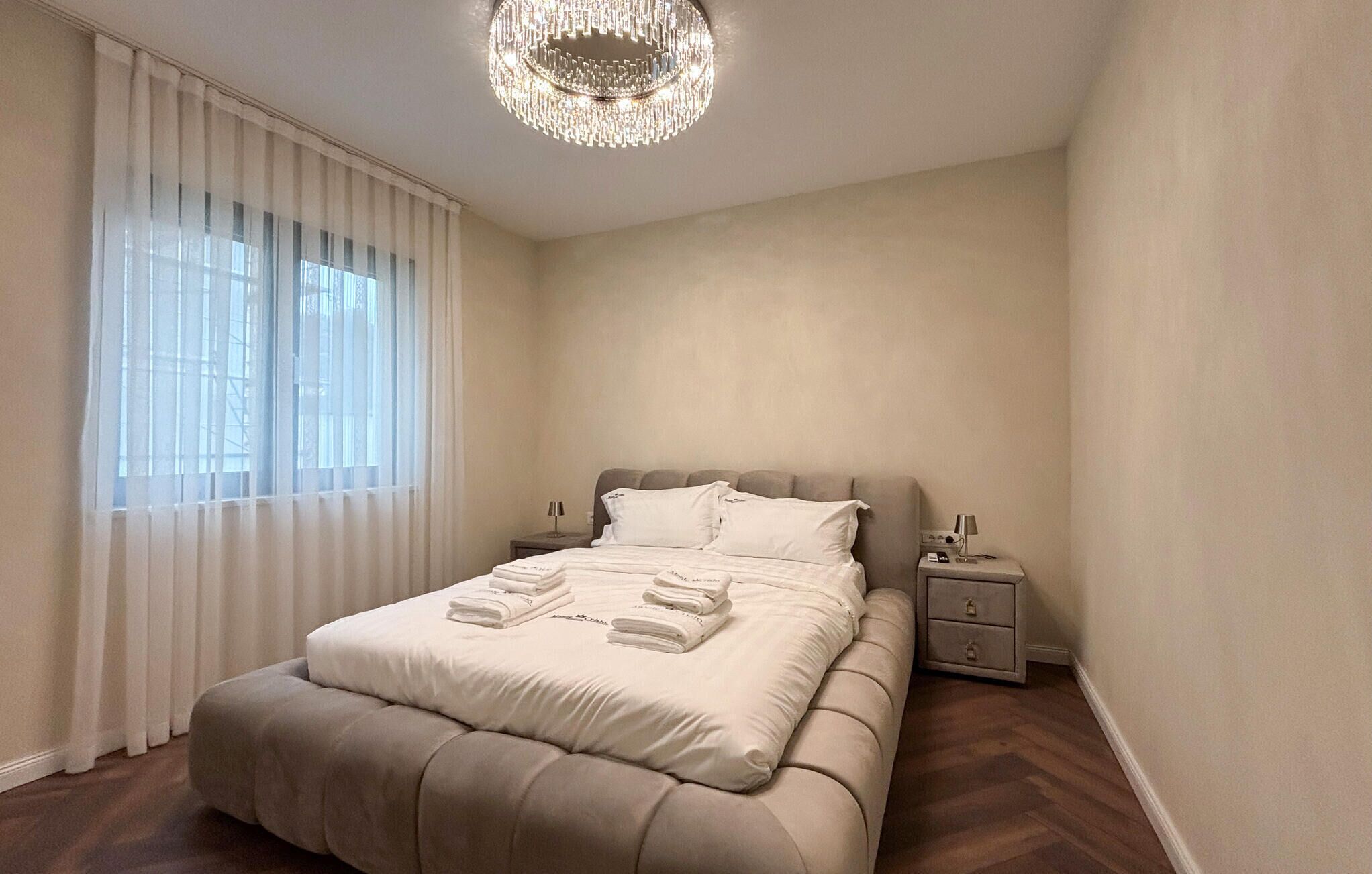 Une chambre à coucher bien aménagée, avec un grand lit, des tables de chevet et un lustre.