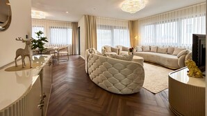 A spacious living room with a large sofa, a round coffee table, and a decorative chair. There is a chandelier, a television, and a plant in the room. - Cozy apartment in Rovinj with house sea view (Rovinj)