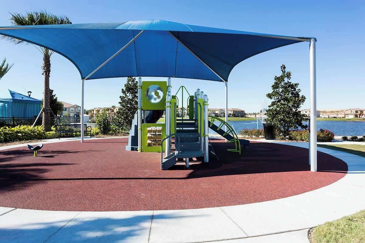 A playground with exercise equipment, a covered seating area, and a view of the water.