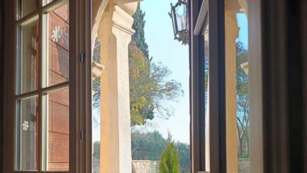 An open wooden door leading to a courtyard with a stone wall, a small tree, and a lamp post. - Villa Dorigny Dimora Storica (Verona)