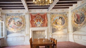 A dining room with a wooden table, chairs, a candelabra, and classical wall paintings. - Villa Dorigny Dimora Storica (Verona)
