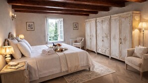 A bedroom with a large bed, a wardrobe, a chair, and a nightstand with a lamp. - Villa Dorigny Dimora Storica (Verona)