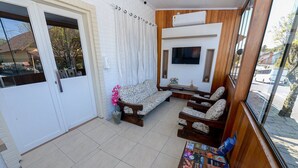 A compact living space with a sofa, armchairs, a TV, and a small table with books. - Pousada Prime Gramado (Gramado)