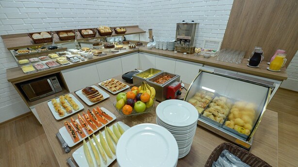 A buffet with various food items, including fruits, pastries, and a coffee station. - Pousada Prime Gramado (Gramado)