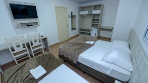 A hotel room with two beds, a TV, a desk, and a wardrobe. - Pousada Prime Gramado (Gramado)