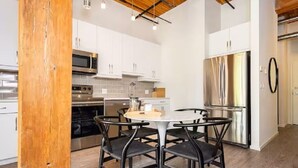 Una cocina moderna con armarios blancos, electrodomésticos de acero inoxidable y una mesa redonda con cuatro sillas.