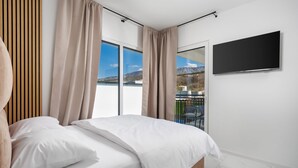 A bedroom with a bed, curtains, a TV, and a view of mountains. - Nice home in Jadranovo (Jadranovo)