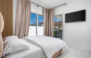 A bedroom with a bed, curtains, a TV, and a view of mountains. - Nice home in Jadranovo (Jadranovo)