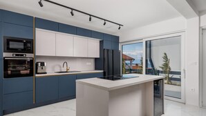 A modern kitchen with a central island, built-in appliances, and a large sliding glass door leading to a balcony. - Nice home in Jadranovo (Jadranovo)