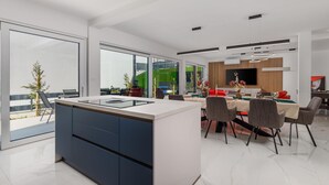 A modern kitchen with a central island, dining area with chairs, and large windows. - Nice home in Jadranovo (Jadranovo)