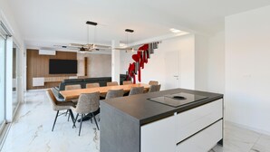 A modern kitchen with a central island, a dining area with a long table and chairs, and a living area with a sofa and TV. - Pet friendly home in Jadranovo with sauna (Jadranovo)